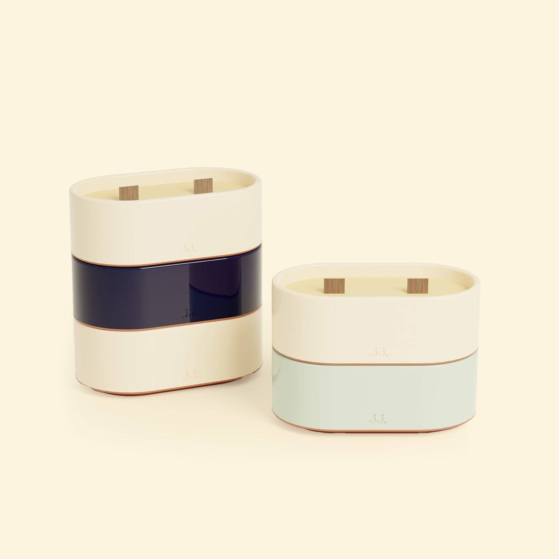Bougies Totem S Beige ivoire – Citronnelle & Citron, Bleu marine – Citronnelle & Sel de mer et Vert d’eau – Citronnelle & Eucalyptus, deux bougies ovales à double mèche en bois, posées sur un fond beige clair. 