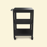 Petite desserte de plancha en métal noir avec trois niveaux de rangement et roulettes pivotantes, présentée de face sur fond uni clair.