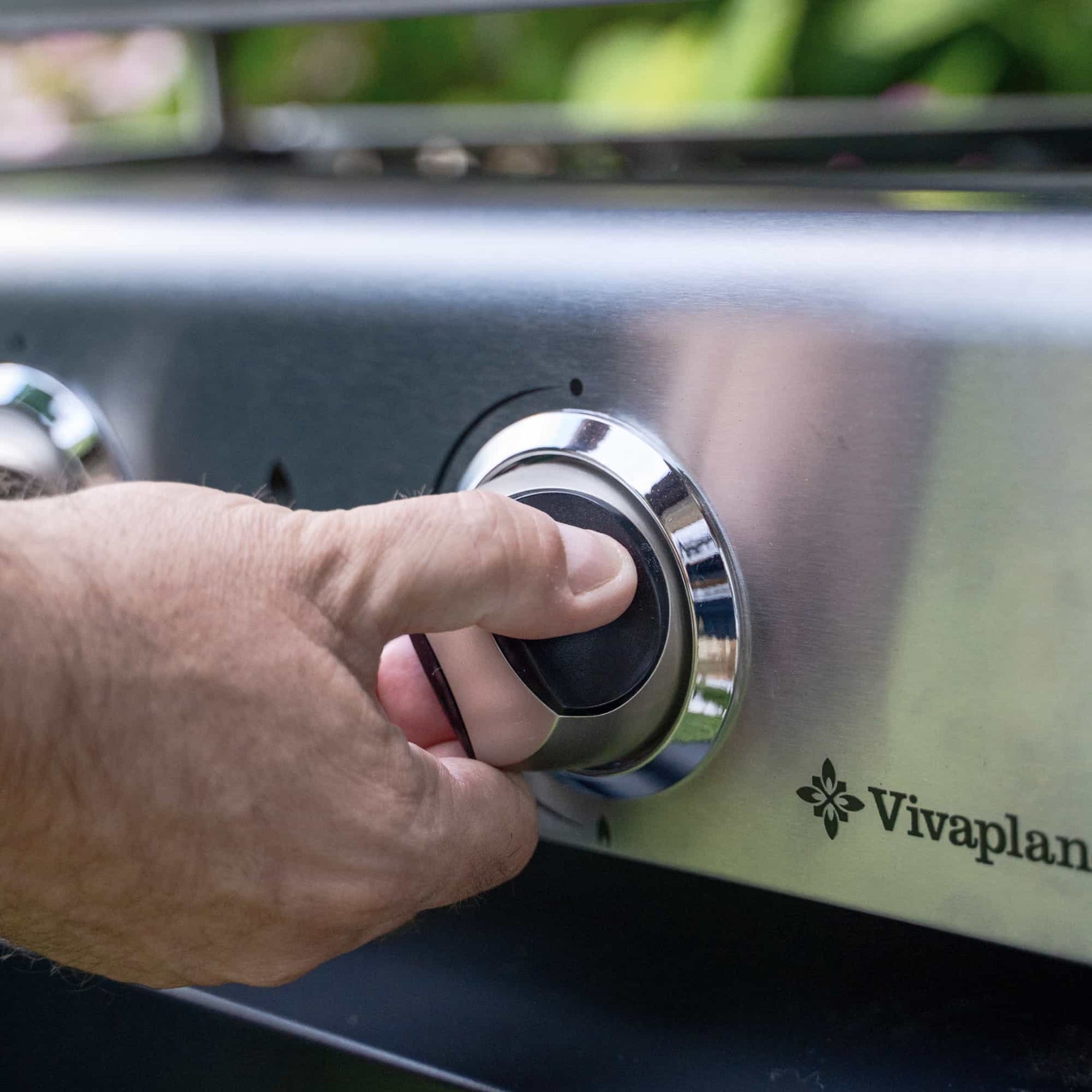 Gros plan sur une main ajustant la molette de contrôle d’une plancha gaz Vivaplancha en acier inoxydable.